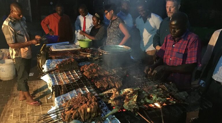 Suya grilling over charcoal at an outdoor spot in Abuja at night